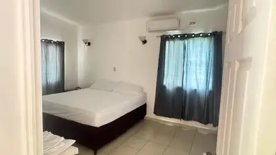 a small bedroom with a bed and a window at Golden Sunset House in Acajutla