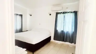 a bedroom with a white bed and a window at Golden Sunset House in Acajutla