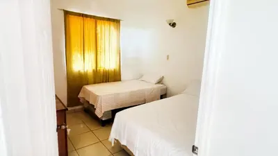 a small room with two beds and a window at Golden Sunset House in Acajutla