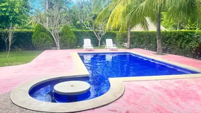 a swimming pool with two chairs in a yard at Golden Sunset House in Acajutla
