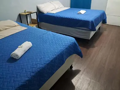 two beds in a room with blue comforter at Hostal Venezuela in San Salvador