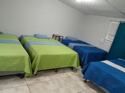 a room with four beds with green and blue covers at Hostal Venezuela in San Salvador