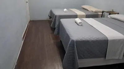 three beds in a room with wood flooring at Hostal Venezuela in San Salvador
