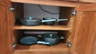 two pots and pans inside of a wooden cabinet at Rancho Joya Del Mar in Sonsonate