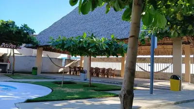 a resort with chairs and a building with a straw roof at Rancho Joya Del Mar in Sonsonate