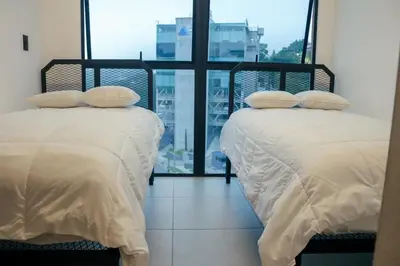two beds in a room with a large window at Park Tower 804 in Nuevo Cuscatlán