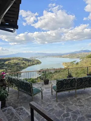 a balcony with two benches and a view of a river at Hotel Vista Hermosa Suchitoto in Suchitoto