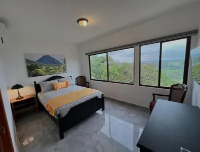 a bedroom with a bed and large windows at Hotel Vista Hermosa Suchitoto in Suchitoto
