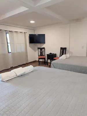 a bedroom with two beds and a flat screen tv at Hotel Vista Hermosa Suchitoto in Suchitoto