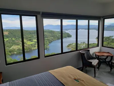 a bedroom with large windows with a view of a lake at Hotel Vista Hermosa Suchitoto in Suchitoto