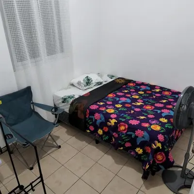 a bed with a floral blanket and a chair in a room at Santa Ana Maquilishuat in Santa Ana
