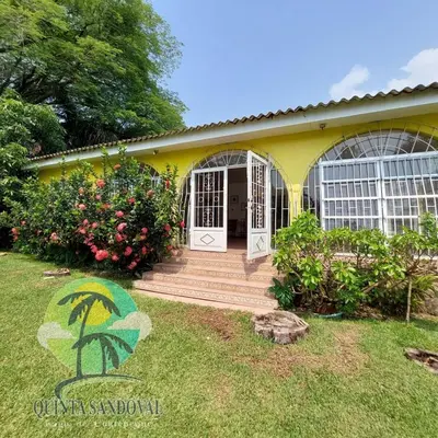a yellow house with a porch and a yard at Quinta Sandoval Lago de Coatepeque in Santa Ana