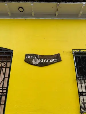 a sign on the side of a yellow wall at Hostal El Amate #3 in Suchitoto