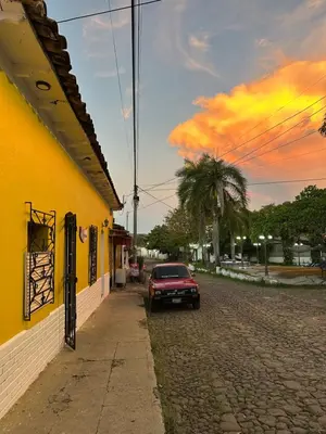 a red car parked next to a yellow building at Hostal El Amate #3 in Suchitoto