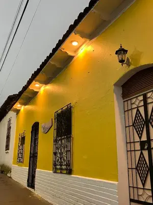 a yellow building with a door and a window at Hostal El Amate #3 in Suchitoto