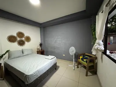 a bedroom with a bed and a fan and a window at Macaw Stay Room in Sonzacate