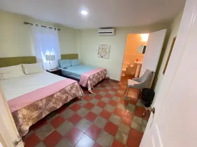 a bedroom with two beds and a chair in it at Hotel y Restaurante Ocean Corner in El Zonte