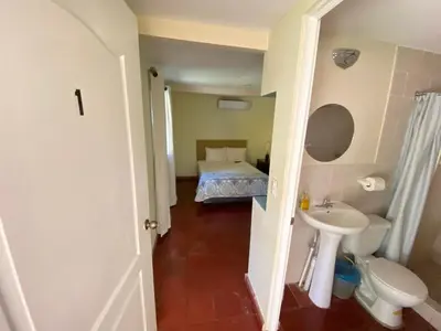a small bathroom with a bed and a toilet and a sink at Hotel y Restaurante Ocean Corner in El Zonte