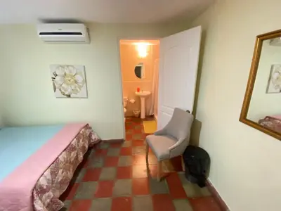 a bedroom with a bed and a chair and a mirror at Hotel y Restaurante Ocean Corner in El Zonte