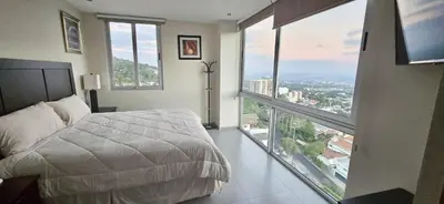 a bedroom with a large bed and large windows at The Sky View in San Salvador