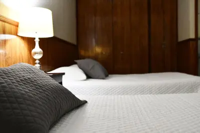 a bedroom with two beds and a lamp on a table at Hotel Manantiales El Salvador in San Salvador
