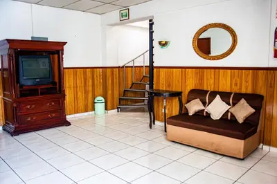 a living room with a couch and a tv at Hotel Manantiales El Salvador in San Salvador