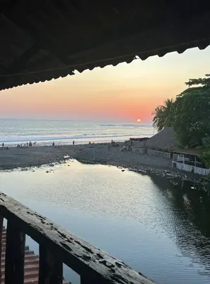 a view of the beach at sunset from a deck at Karma Muse Hotel in La Libertad