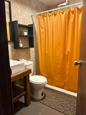 a bathroom with an orange shower curtain and a toilet at Estero View Beach House in Barra de Santiago