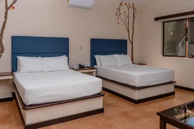 two beds in a room with blue headboards at Boca Olas Resort Villas in La Libertad