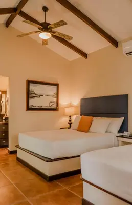 a bedroom with two beds and a ceiling fan at Boca Olas Resort Villas in La Libertad