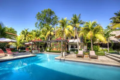 a swimming pool in front of a house with palm trees at Boca Olas Resort Villas in La Libertad