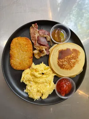 a black plate of breakfast food with eggs bacon and toast at Eco Suites El Zonte in La Libertad