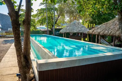 a swimming pool with trees and huts at Eco Suites El Zonte in La Libertad