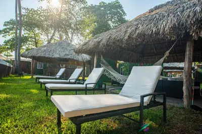 a row of chaise lounges with straw umbrellas at Eco Suites El Zonte in La Libertad