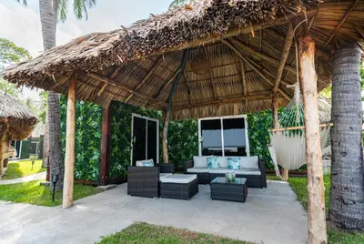 an outdoor seating area with a thatched roof at Eco Suites El Zonte in La Libertad
