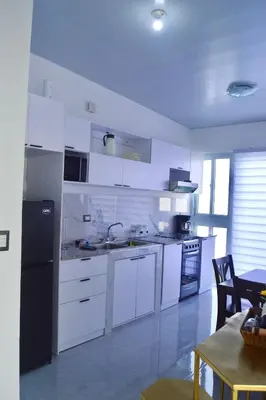 a kitchen with white cabinets and a black refrigerator at sophia by aby House in San Miguel