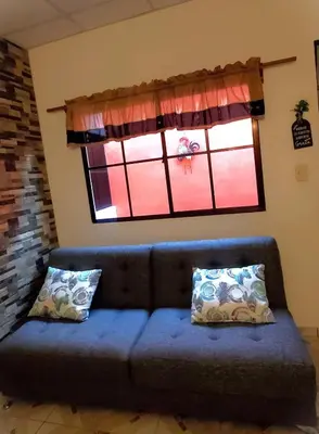 a blue couch in a living room with a window at Altagracia Altagracia in Santa Ana