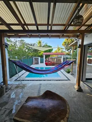 a hammock on a patio with a pool at Wayo ocean view Tamanique house in Tamanique