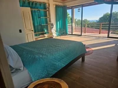 a bedroom with a green bed and a large window at Wayo ocean view Tamanique house in Tamanique