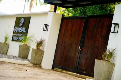 a wooden gate to a house with potted plants at SunSal Garden Surf Hub in El Sunzal