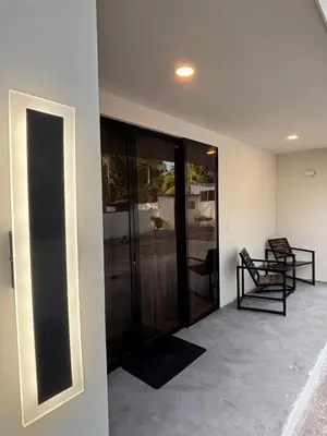 a living room with glass doors and a chair at SunSal Garden Surf Hub in El Sunzal