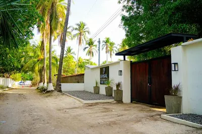 a house with a garage with palm trees in the background at SunSal Garden Surf Hub in El Sunzal