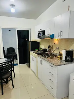 a kitchen with white cabinets and a table and a stove at VillaOriental in San Miguel