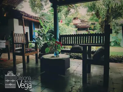 a porch with two benches and a table with a vase at Casona los Vega in Izalco