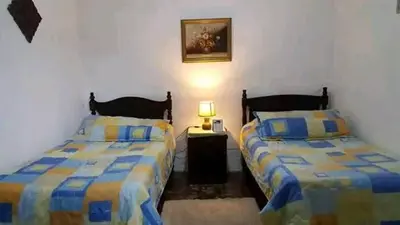 a bedroom with two beds and a table with a lamp at Casona los Vega in Izalco