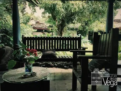a wooden bench with a table with a vase of flowers at Casona los Vega in Izalco