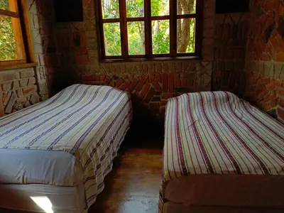 two beds in a room with two windows at cabaña Lechuza café in Juayúa