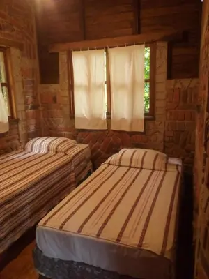 two beds in a room with two windows at cabaña Lechuza café in Juayúa