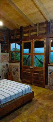a bedroom with a bed in a room with windows at cabaña Lechuza café in Juayúa