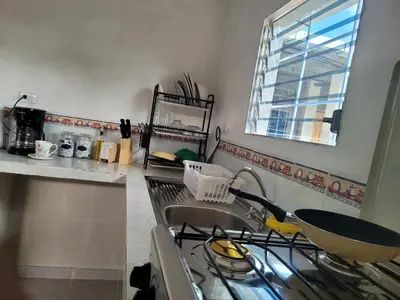 a kitchen with a sink and a stove and a window at Mi pueblo Hostal Nahuizalco in Nahuizalco